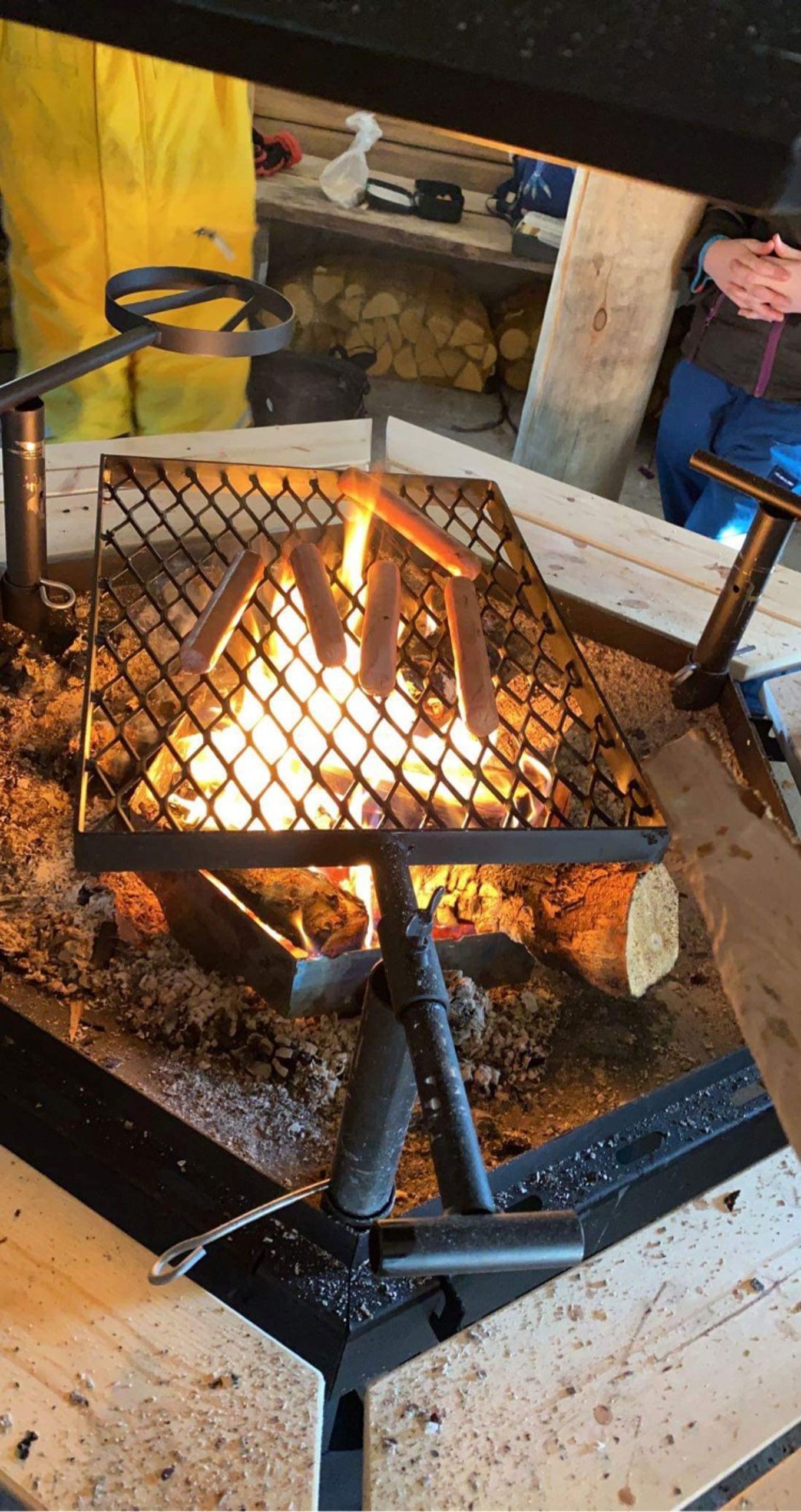 En bålpanne med ild og pølser som ligger og blir grillet