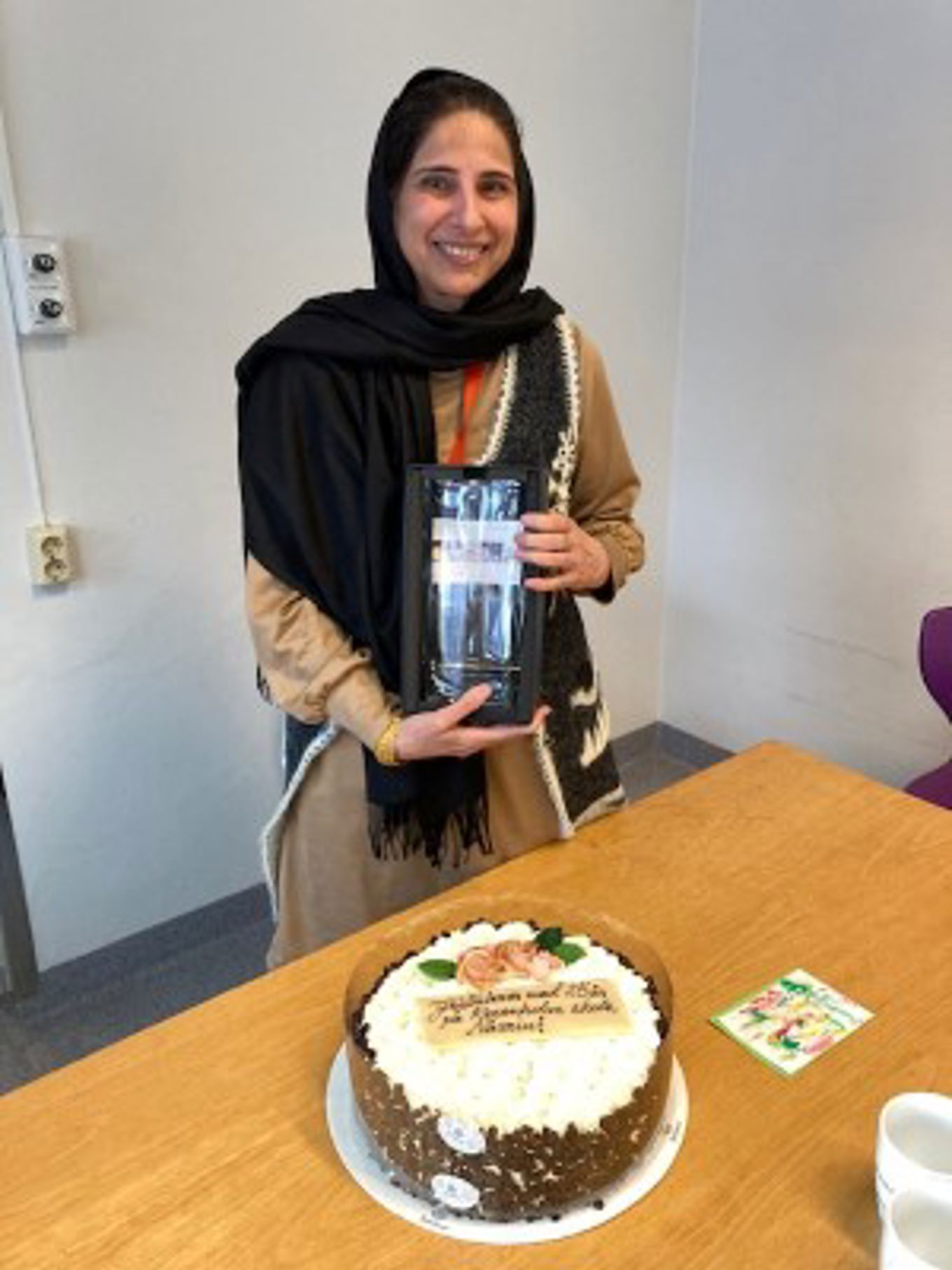 en person som holder en flaske vann ved siden av en kake