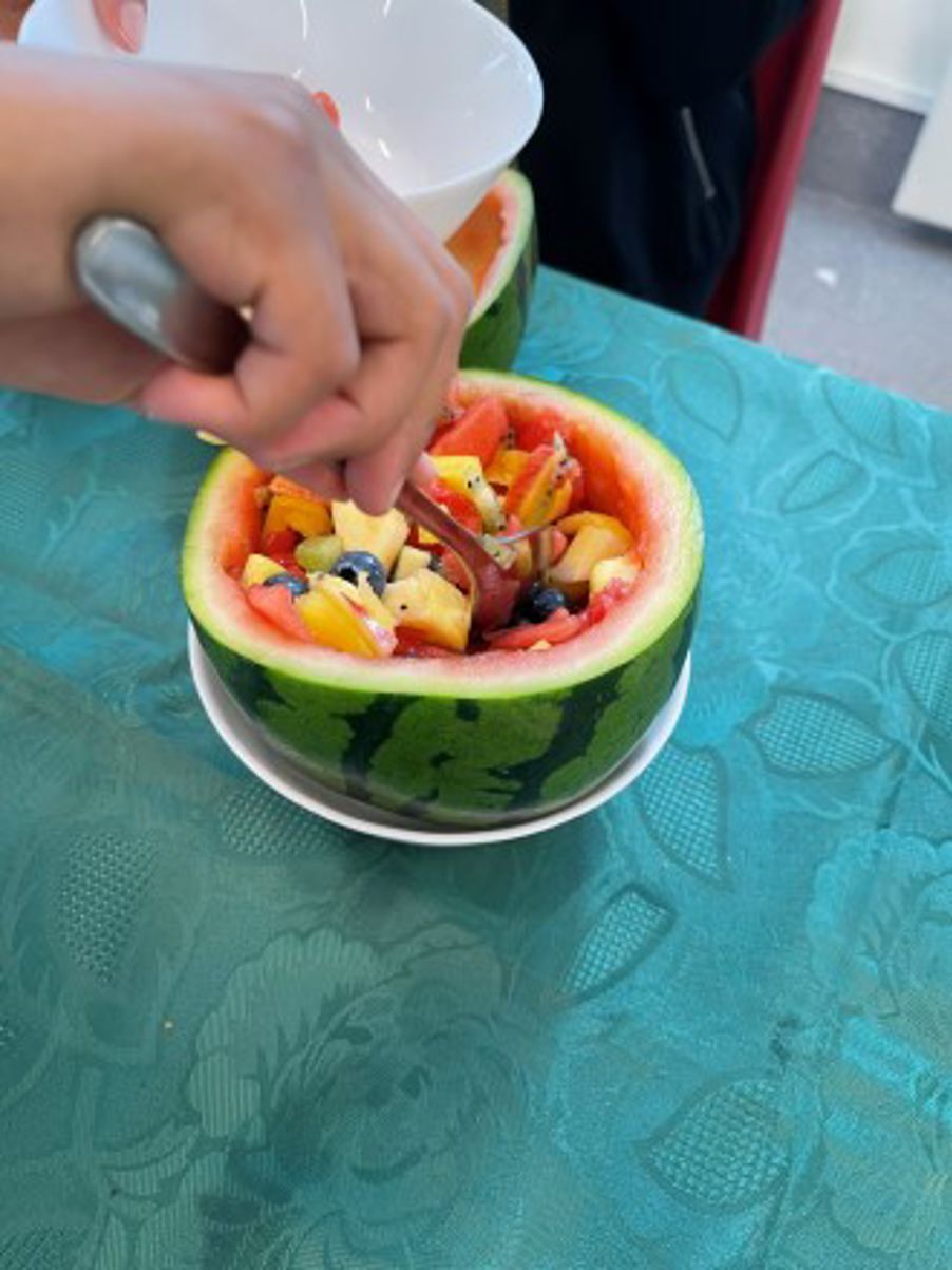 en delt vannmelon som inneholder en fruktsalat hvor en skje er satt nedi for å ta frukten opp med.