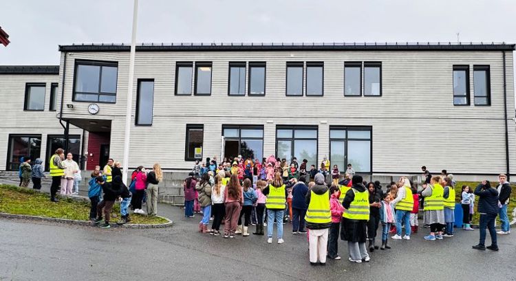 Utenfor administrasjonsbygningen står det mange voksne og barn som hører på at 1.trinn synger for dem.